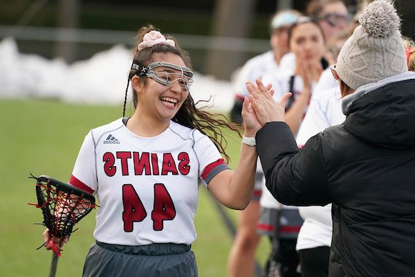Lacrosse player highfiving someone, smiling